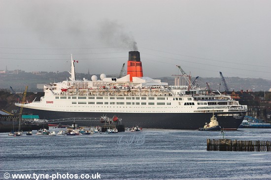 The QE2 turning at the bend in the river before the Shields Ferry, with tugs at the rear assisting.