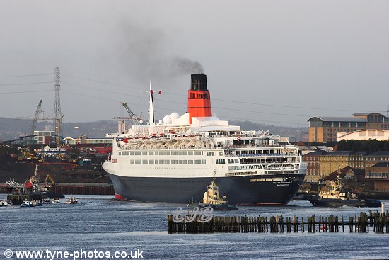 The QE2 turning at the bend in the river before the Shields Ferry, with tugs at the rear assisting.