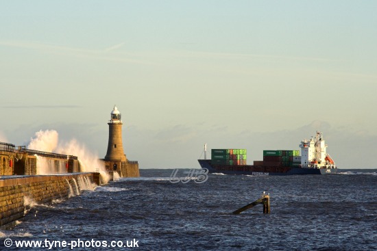 Waves breaking over the pier as the ship passes Tynemouth Lighthouse.