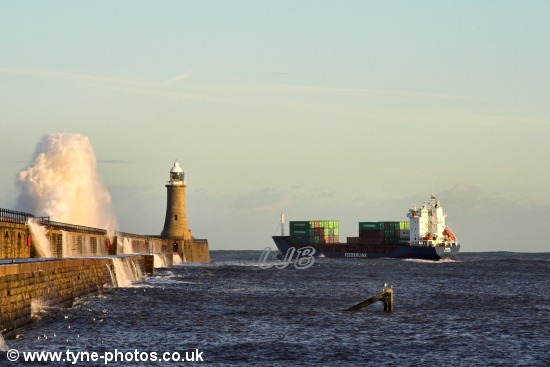 Waves breaking over the pier as the ship passes Tynemouth Lighthouse.