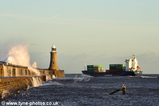 Waves breaking over the pier as the ship passes Tynemouth Lighthouse.