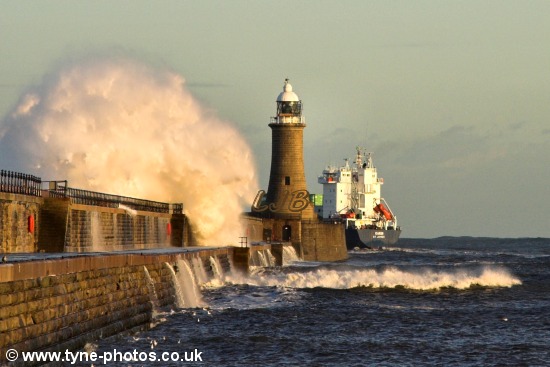 Waves breaking over the pier as the container ship Karin ship passes Tynemouth Lighthouse.